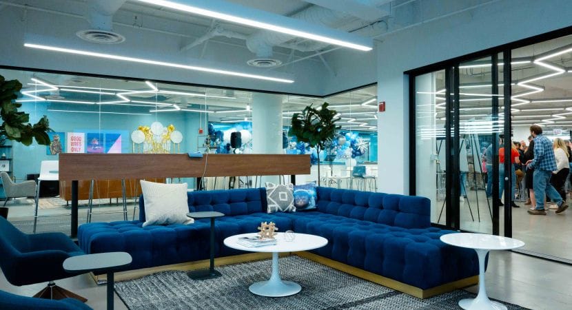 Photo of meeting room with blue sectional sofa and white circular coffee and side tables