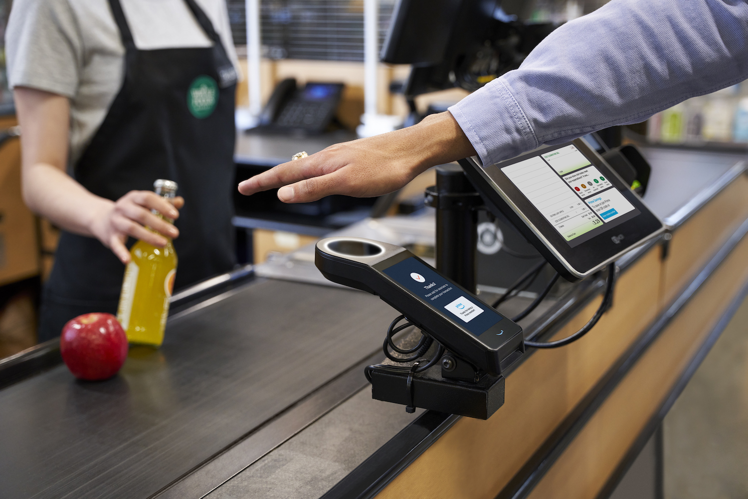 A Whole Foods customer uses their palm to pay using Amazon One.