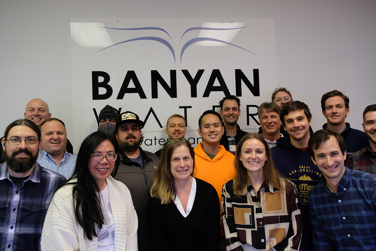 Banyan Water team members in front of a wall with the company logo on it