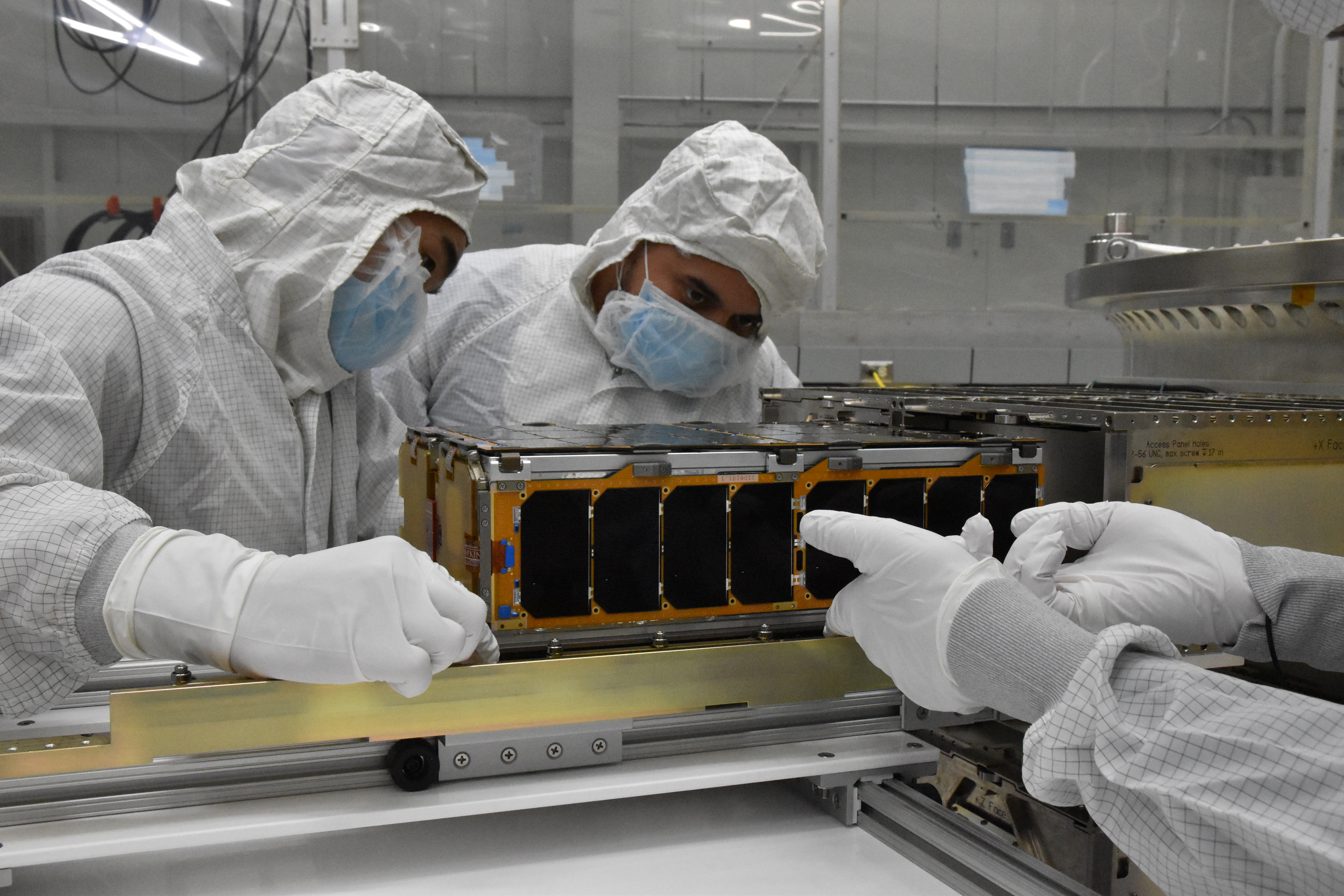 CesiumAstro employees load an active phased array system into a payload dispenser.