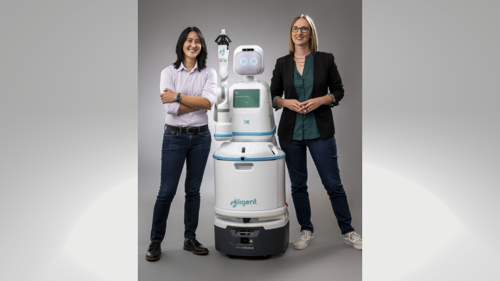 Dr. Andrea Thomaz and Dr. Vivian Chu from Diligent Robotics stand with Moxi.