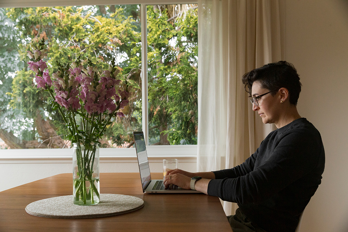 Dropbox team member Rachel Wolan working from home at a table with a vase of flowers on it