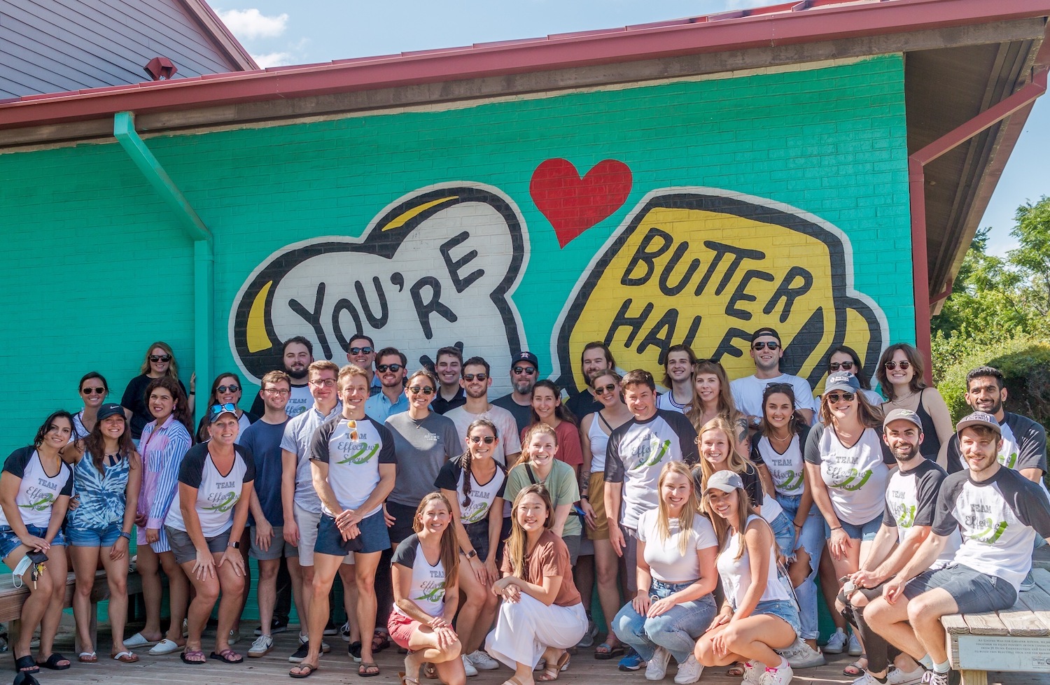 Effective Spend employees pose in front of the “You're My Butter Half” mural in Austin.