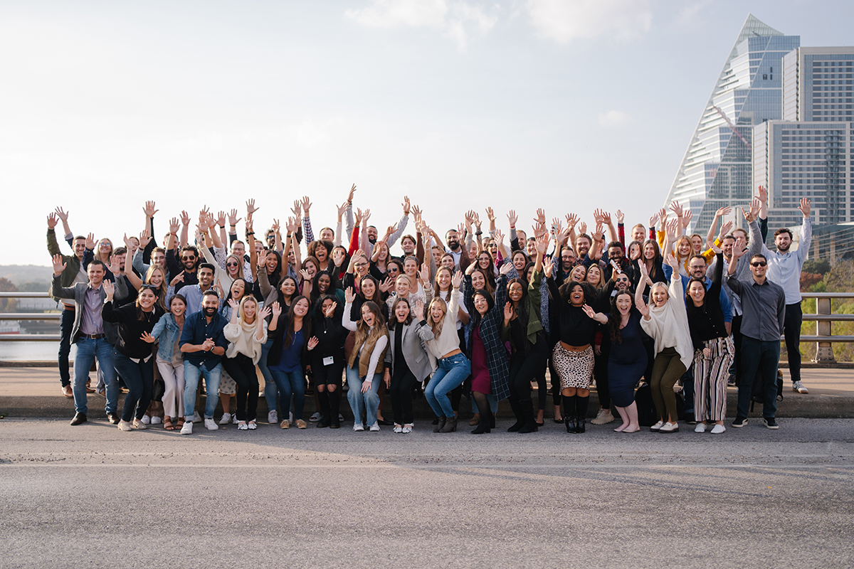 Luxury Presence group photo outside with some team members throwing their arms in the air