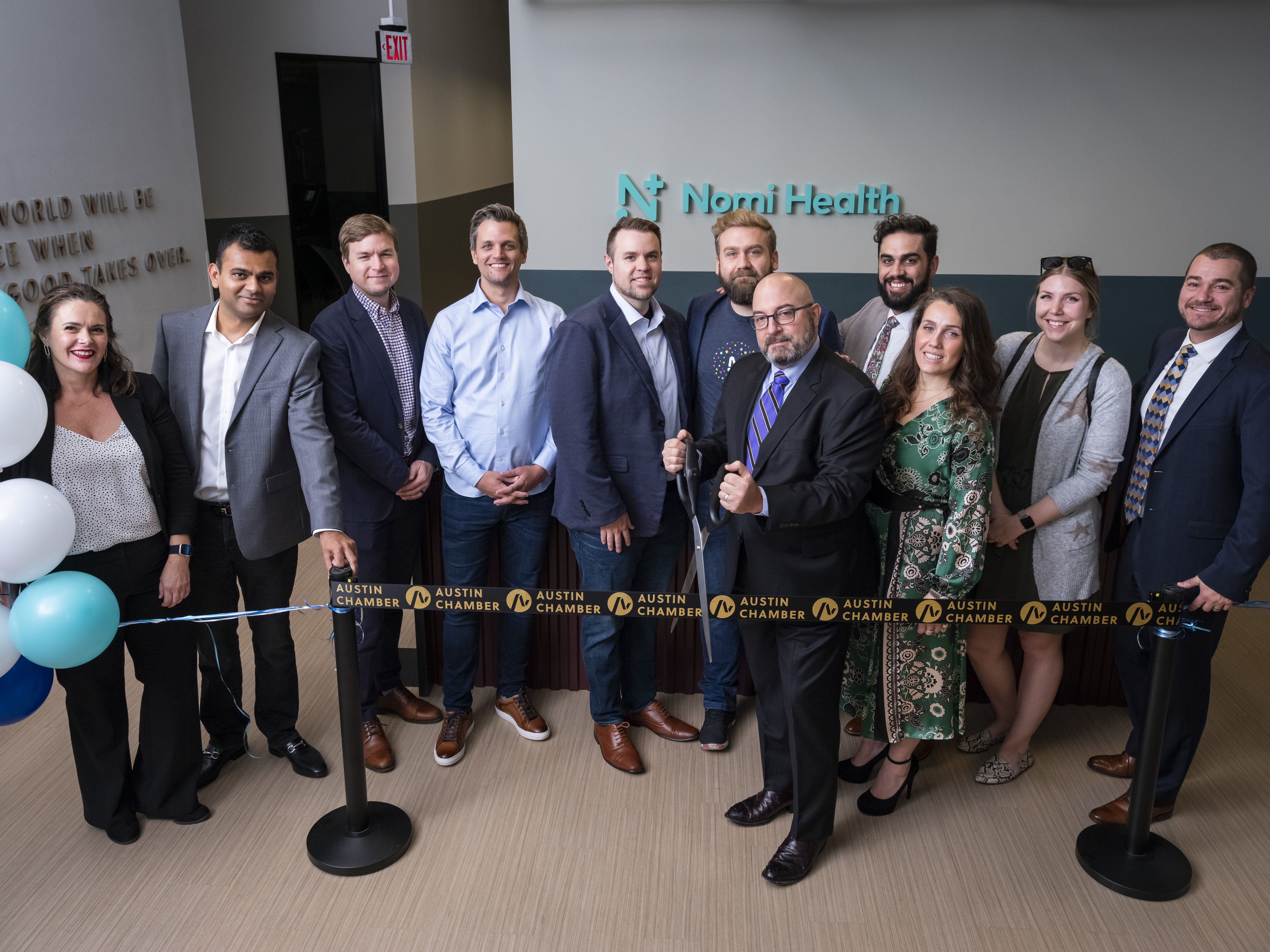 Nomi Health employees gather at its new Austin office for a ribbon cutting ceremony