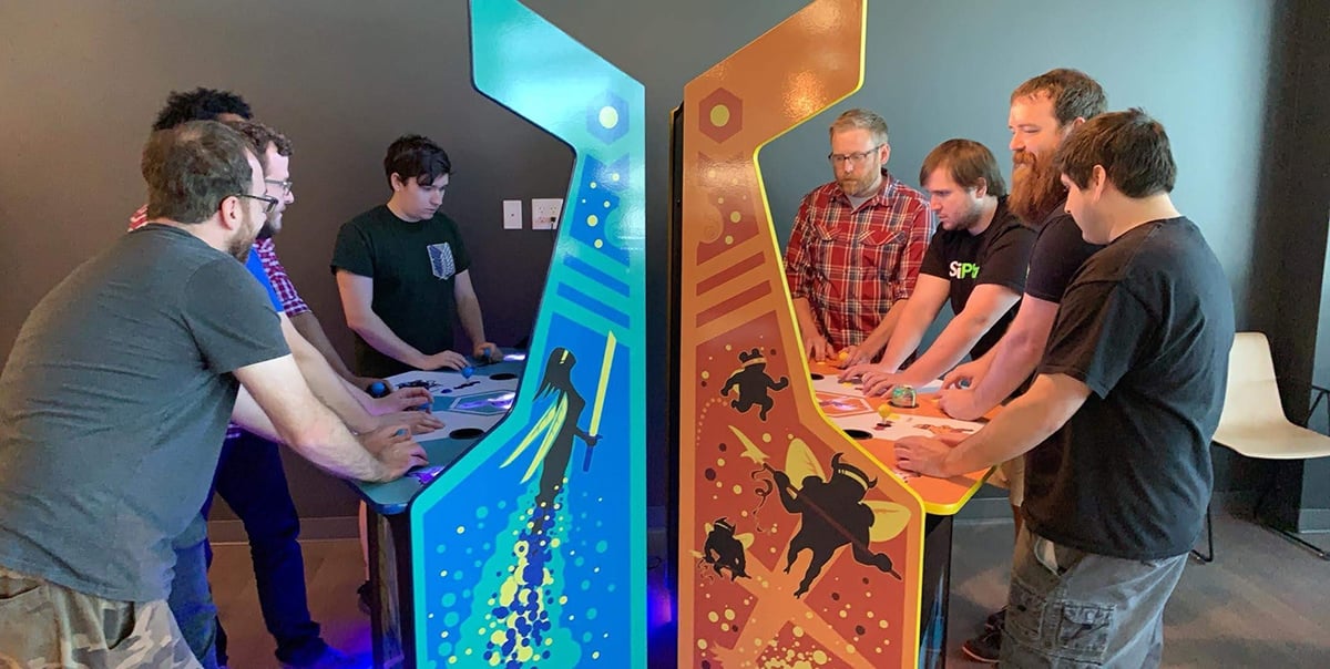 SciPlay team members playing upright video games in the office