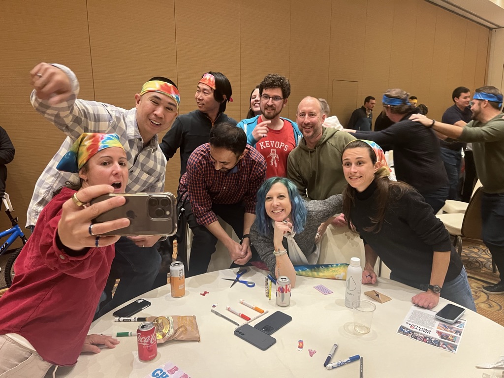 Candid photo of eight team members posing for a selfie around a table with markers wearing colorful items