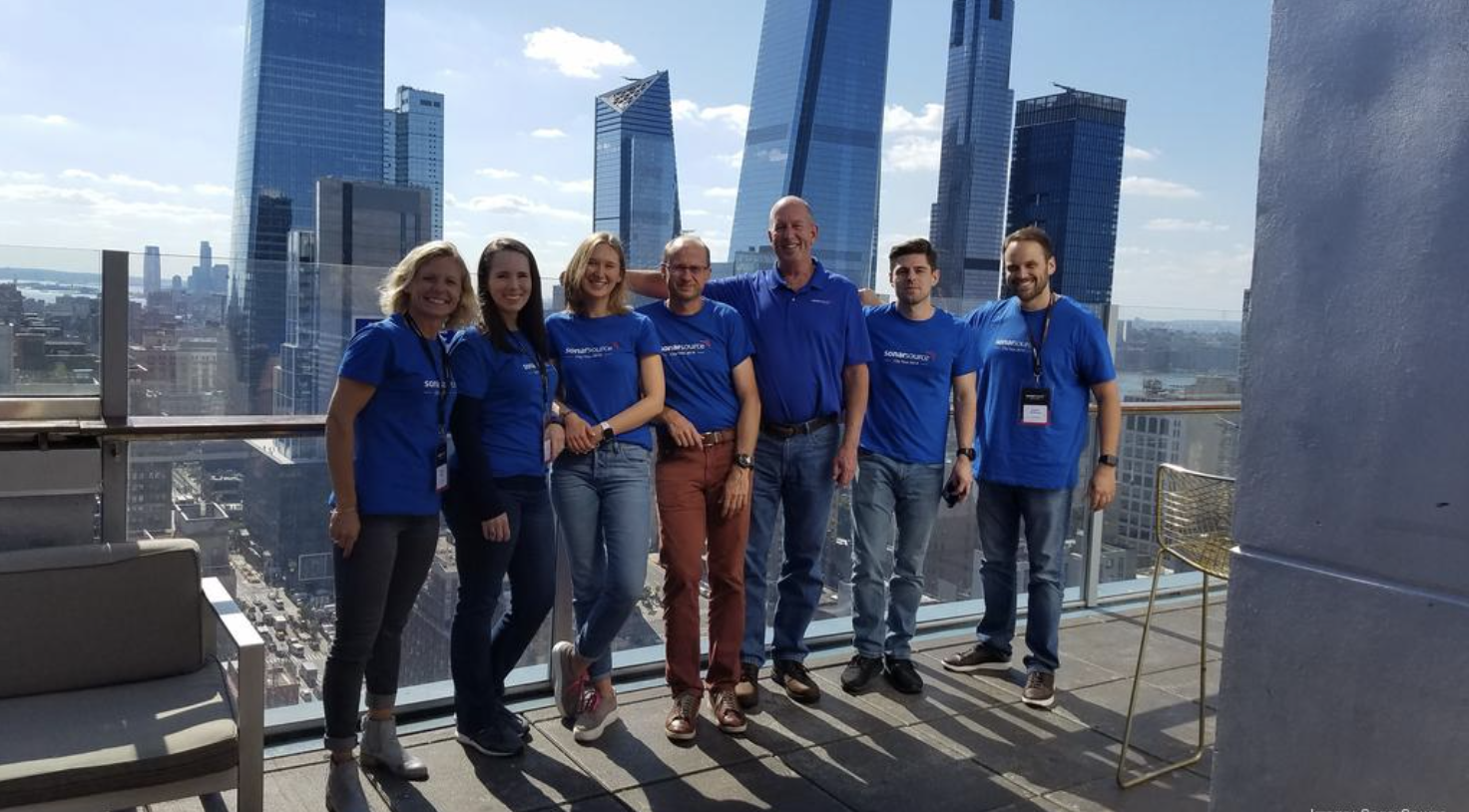 Sonar team standing on balcony with skyscrapers in background.
