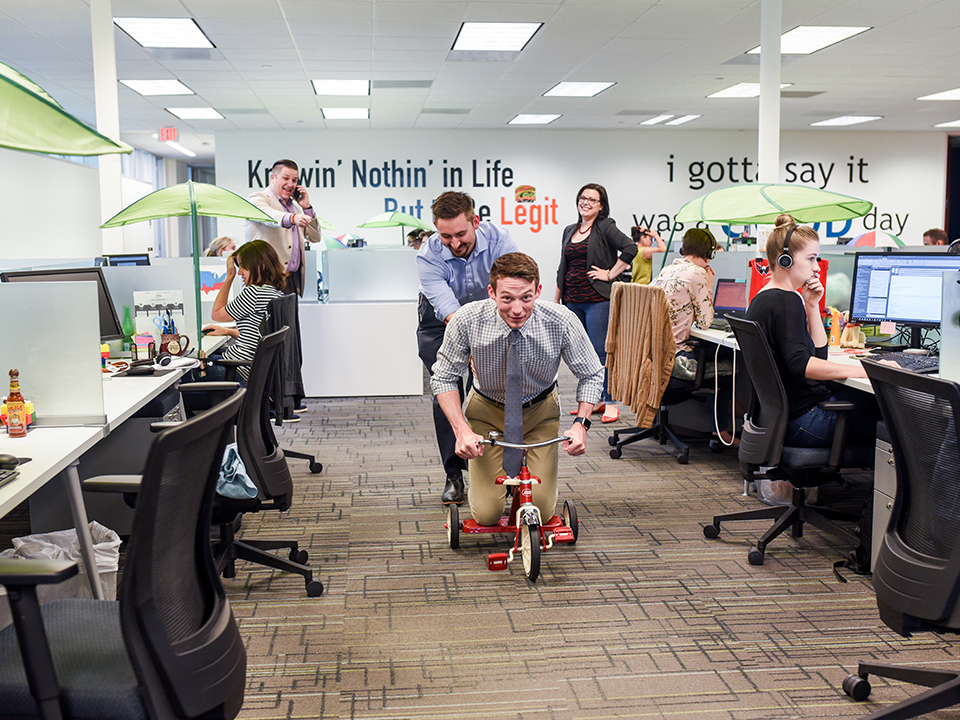 Employees ride a tricycle in Social Solutions' office