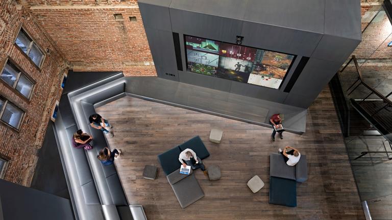 An aerial view of a brick-walled office lobby with televisions on one wall.