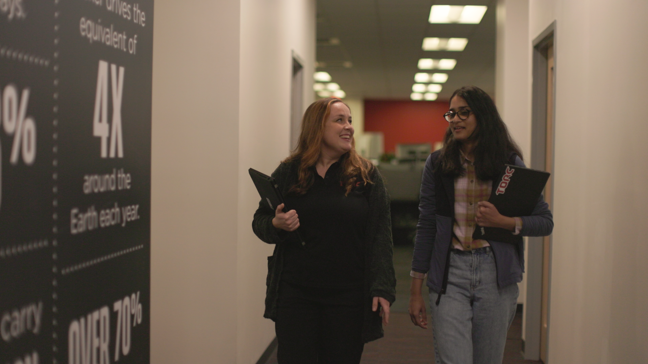 Two Torc Robotics team members chat while walking down an office hallway.