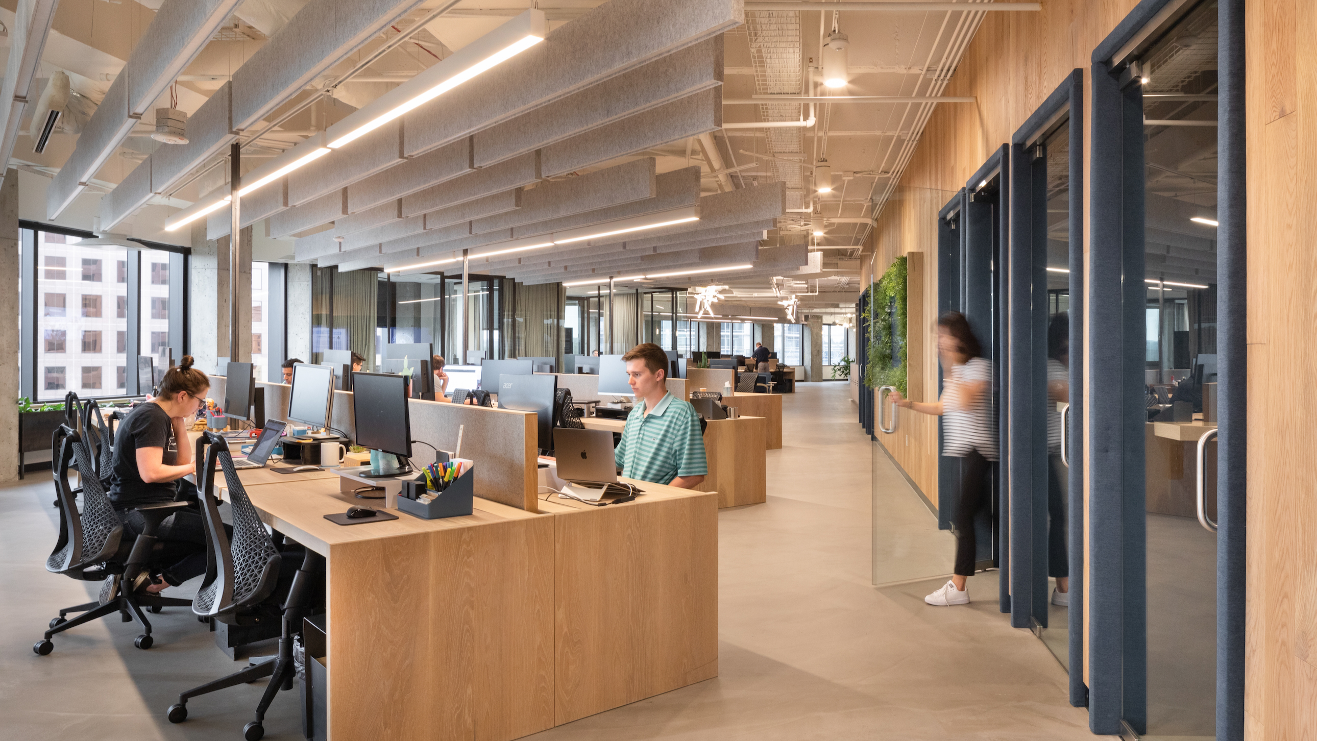  Workrise team members work in a modern, well-lit office space with wooden desks. 