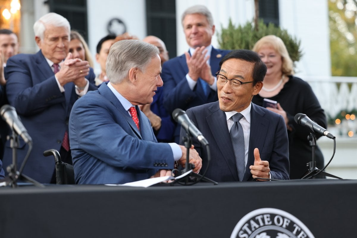 Texas Gov. Greg Abbott shakes hands with Kinam Kim, vice chairman and CEO of Samsung’s device solutions division, during a news conference on Tuesday, Nov. 23.