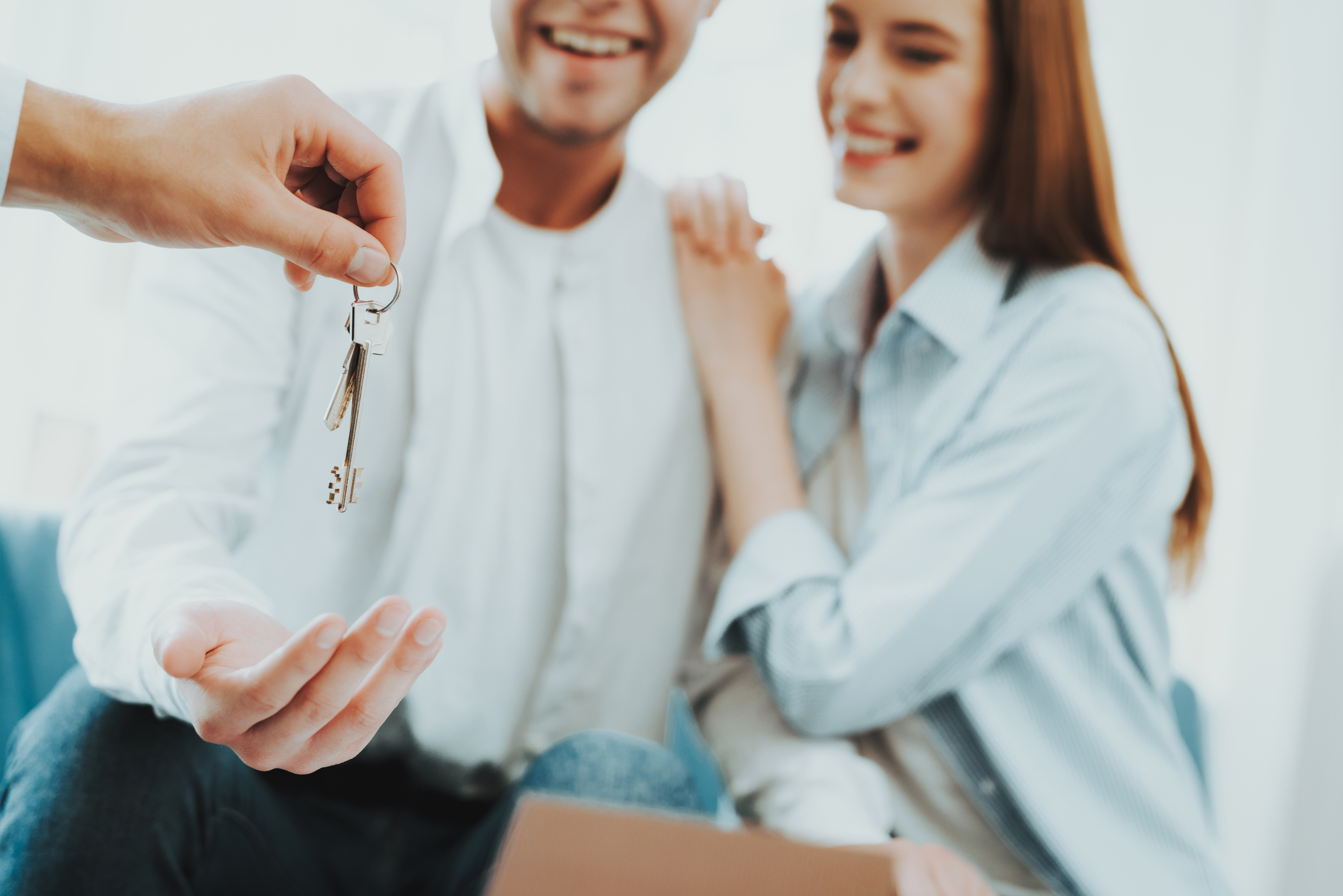 A man hands house keys to a man and woman.