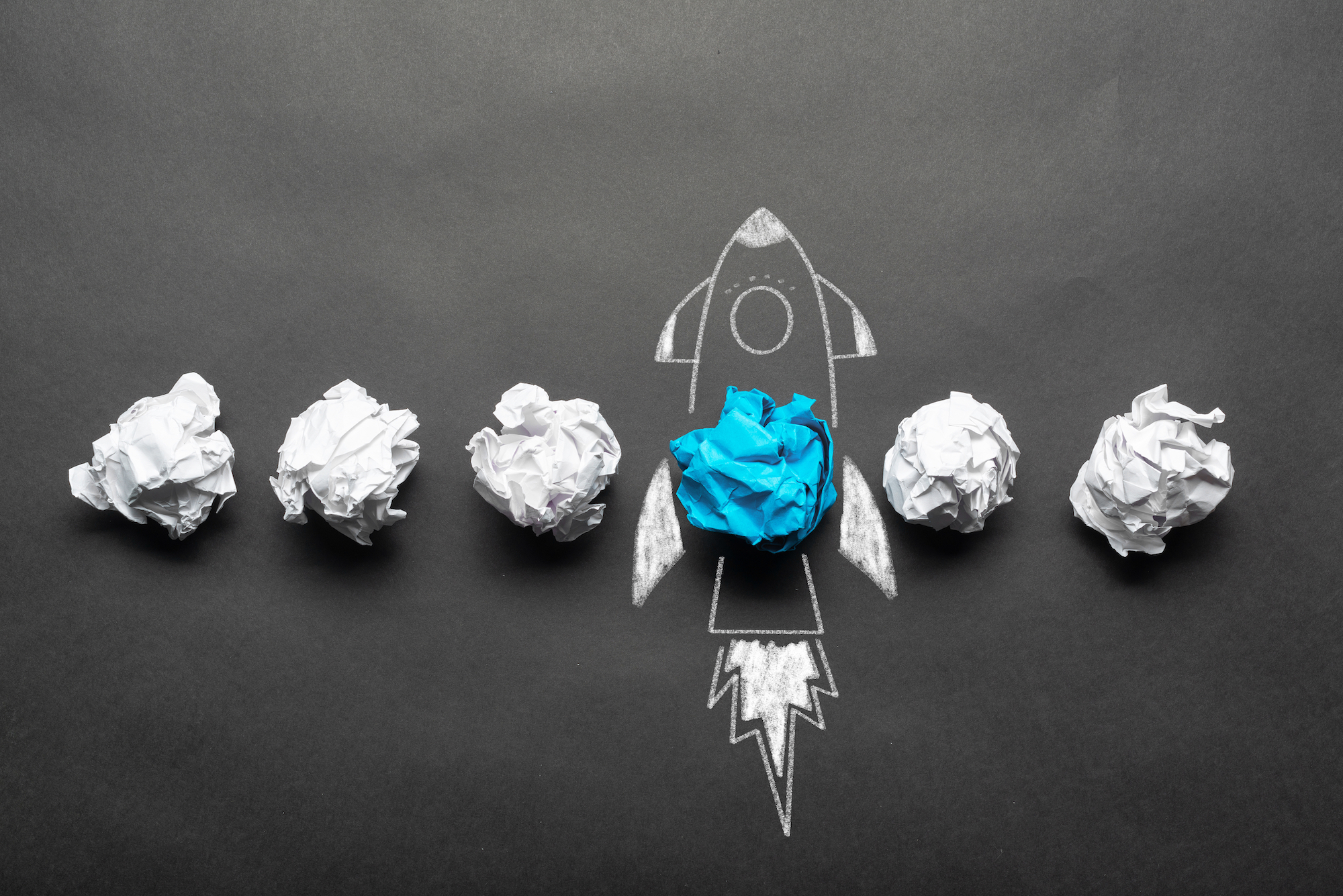 A drawn rocketship surrounded by crumpled pieces of paper, indicating an idea startup.