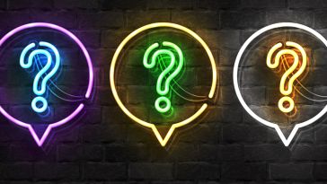 Image of brick wall with a row of three neon lights shaped like question marks within neon light speech bubbles