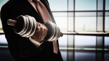 A man in a business suit lifting weights for muscle development.