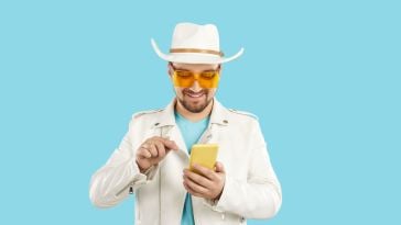 A man in Western wear types on his phone.